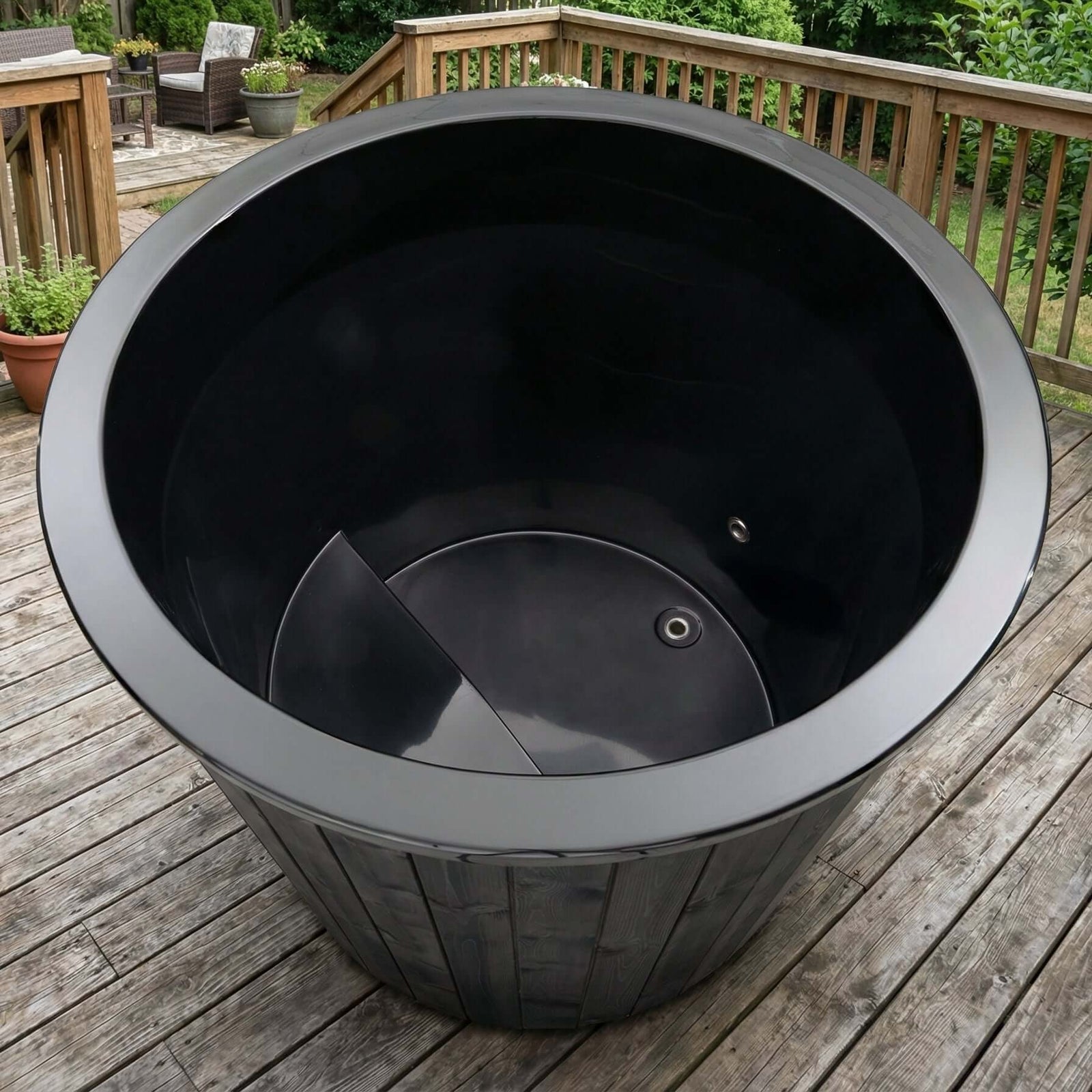 Empty black S1B tub from SaunaLife on a wooden deck with outdoor furniture in the background