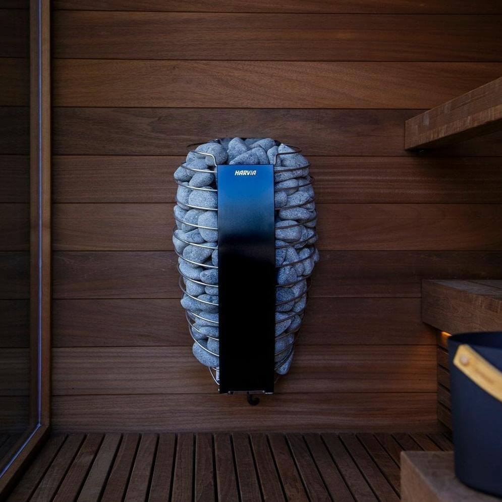 Harvia Spirit electric sauna heater mounted on a wooden wall in the center, wooden benches on the right and a window on the left