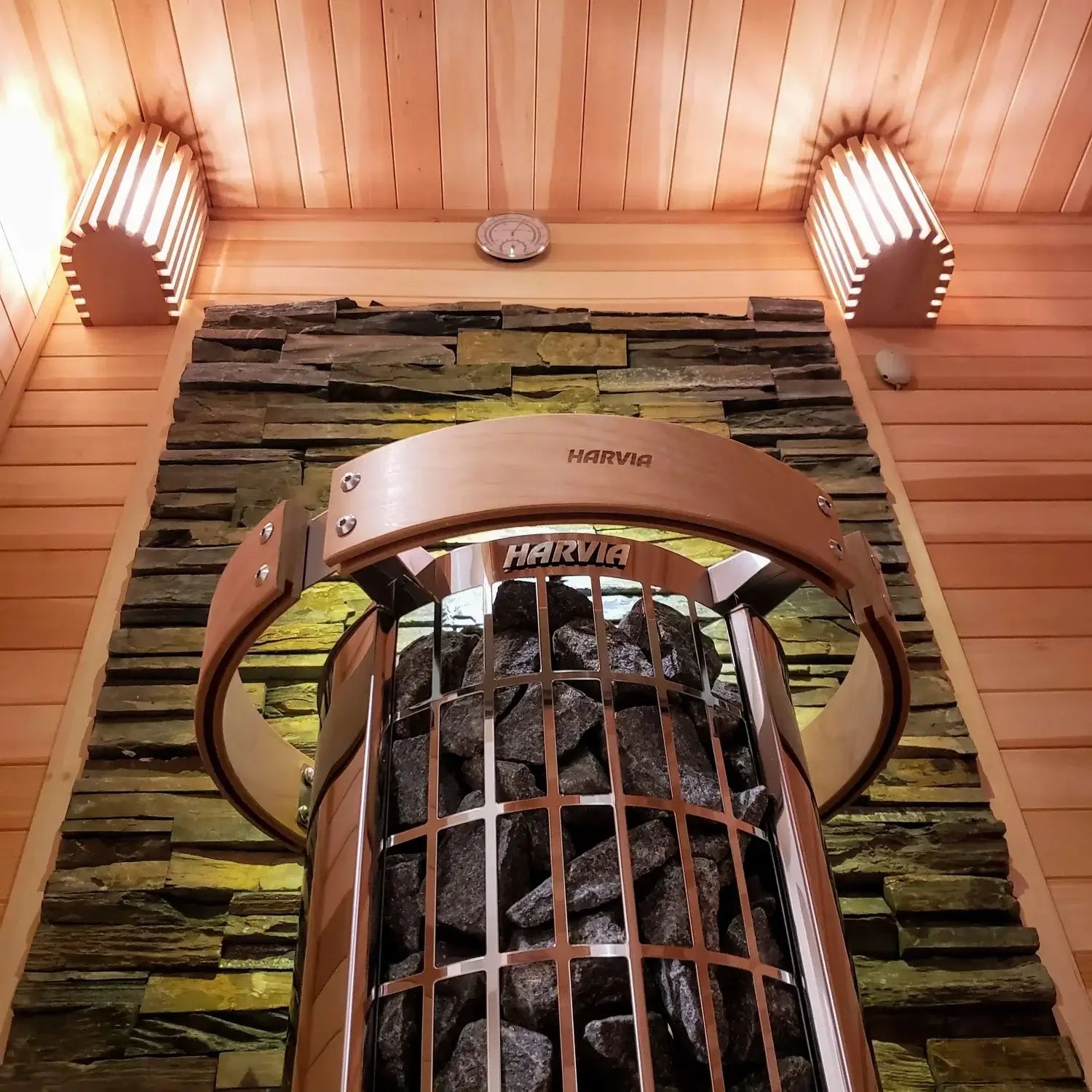 Close-up of Harvia Cilindro Half Series Electric Sauna Heater in a wooden sauna with stone wall background