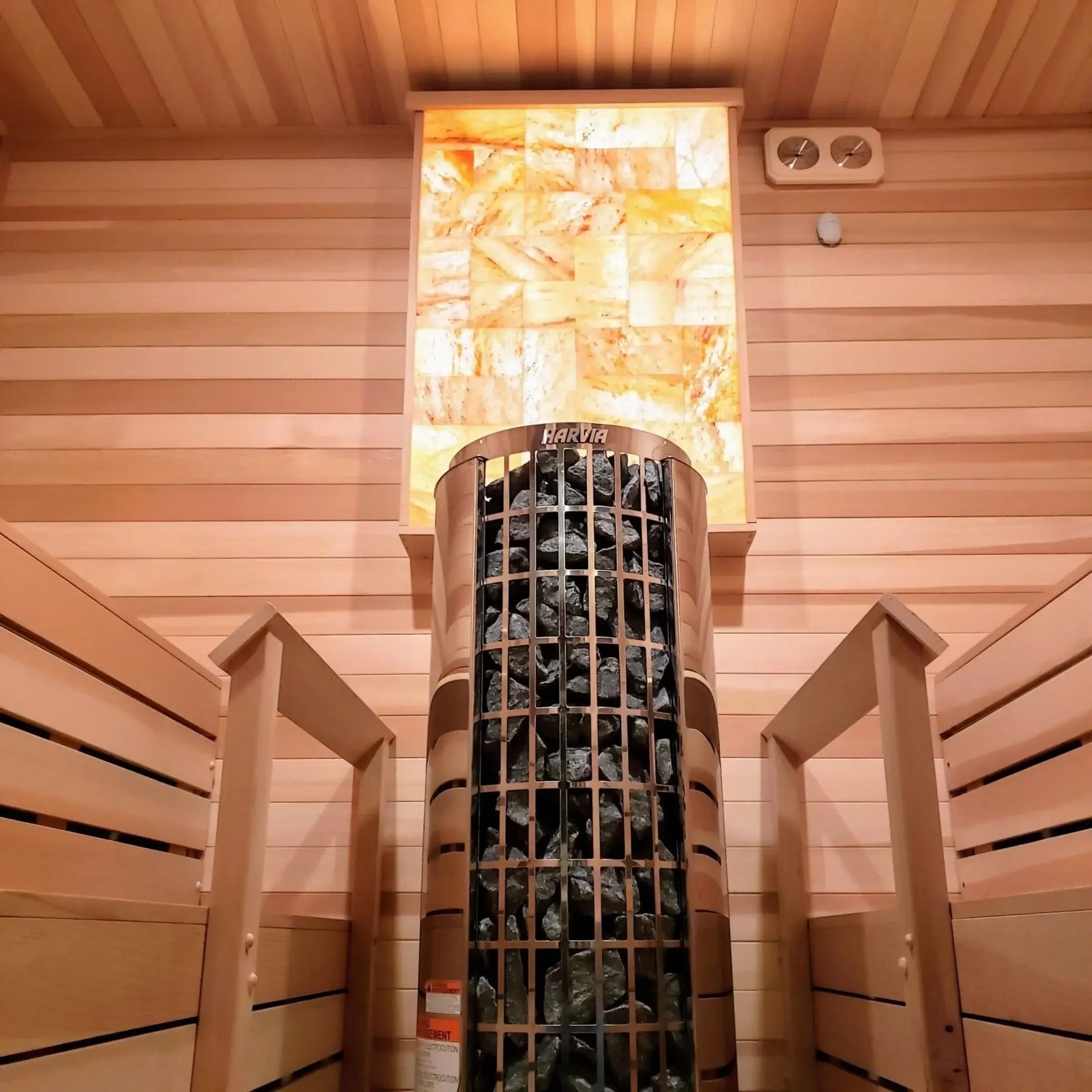 Traditional sauna with wooden interior and Harvia Cilindro half series electric sauna heater with exposed stone pillar