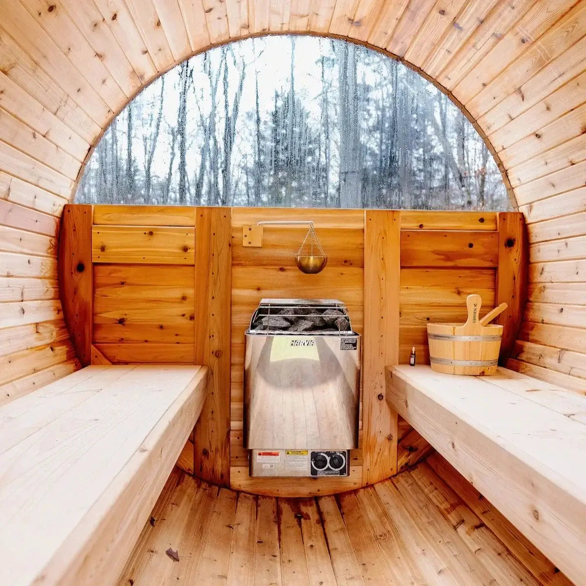 Harvia KIP with built in controls sauna heater in a wooden sauna with benches surrounded by a forest view.