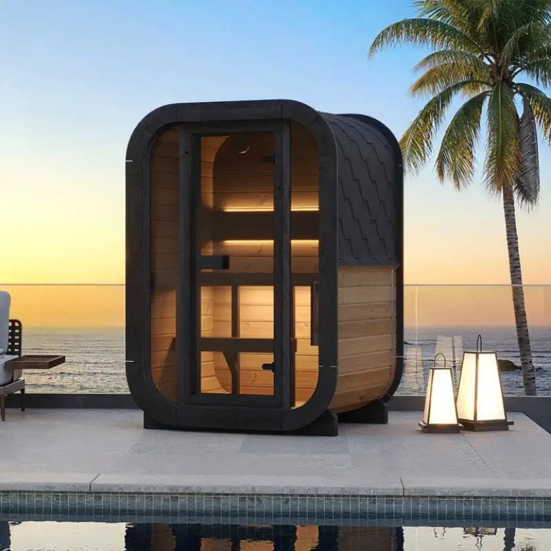 SaunaLife CL3G 2-Person Cube-Series Outdoor Sauna Kit by the pool at sunset with palm trees.