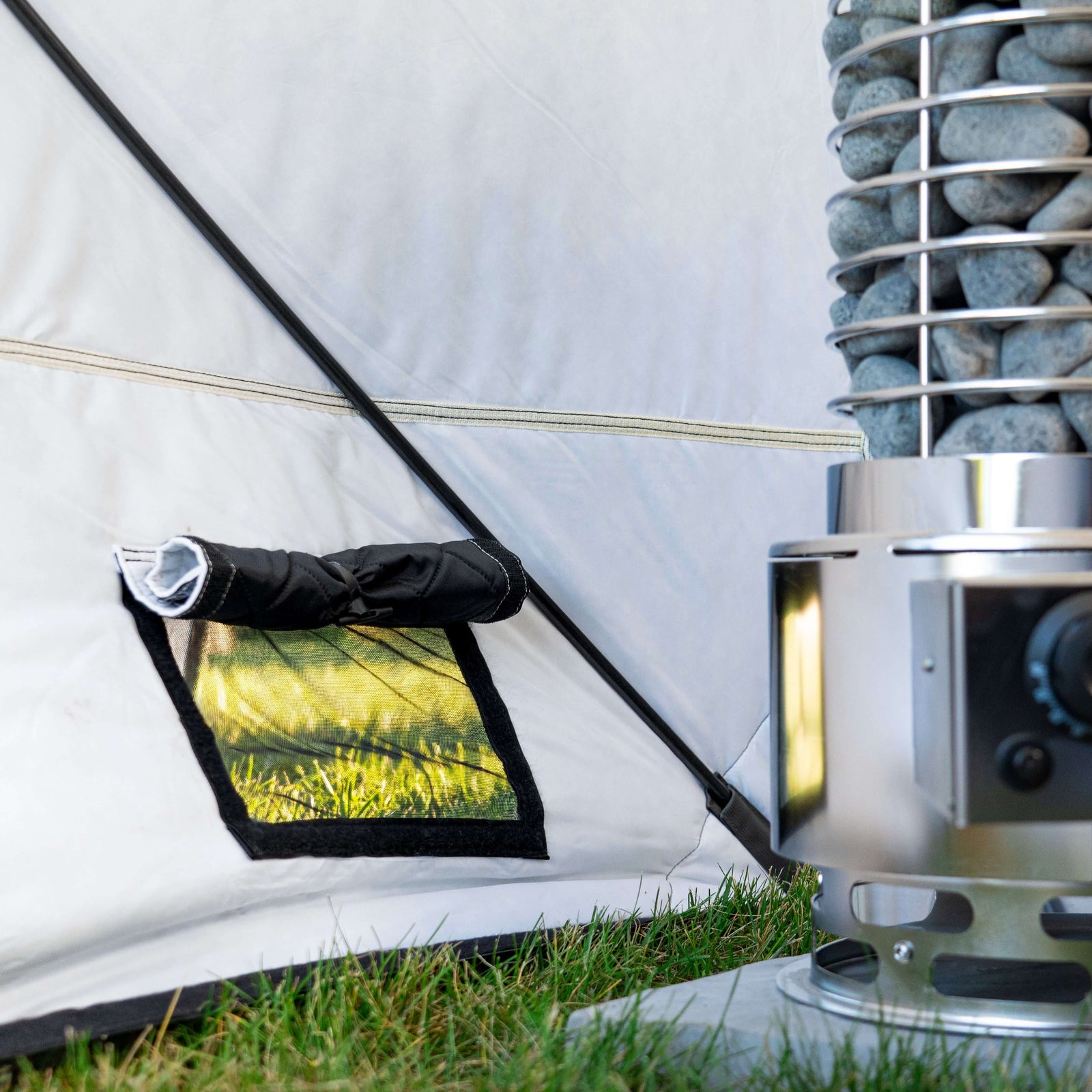Close-up of SaunaLife TITAN SL1 Portable Propane Sauna Heater and tent window, showcasing outdoor setup.