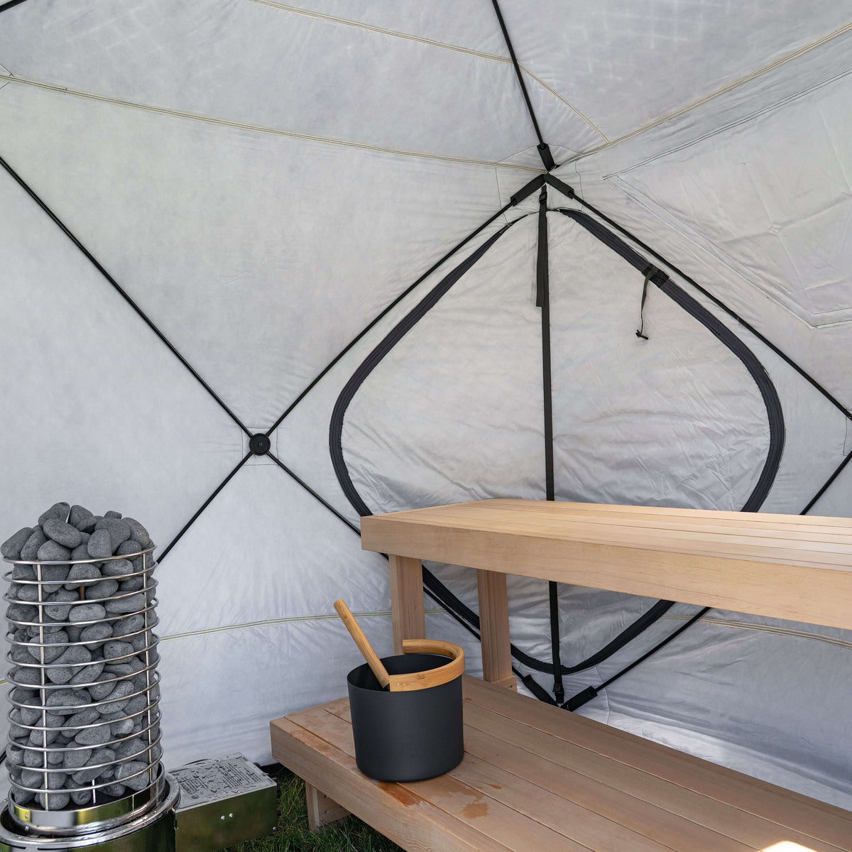 Interior view of SaunaLife SaunaTrekker Portable Sauna Tent with sauna stones and wooden bench.