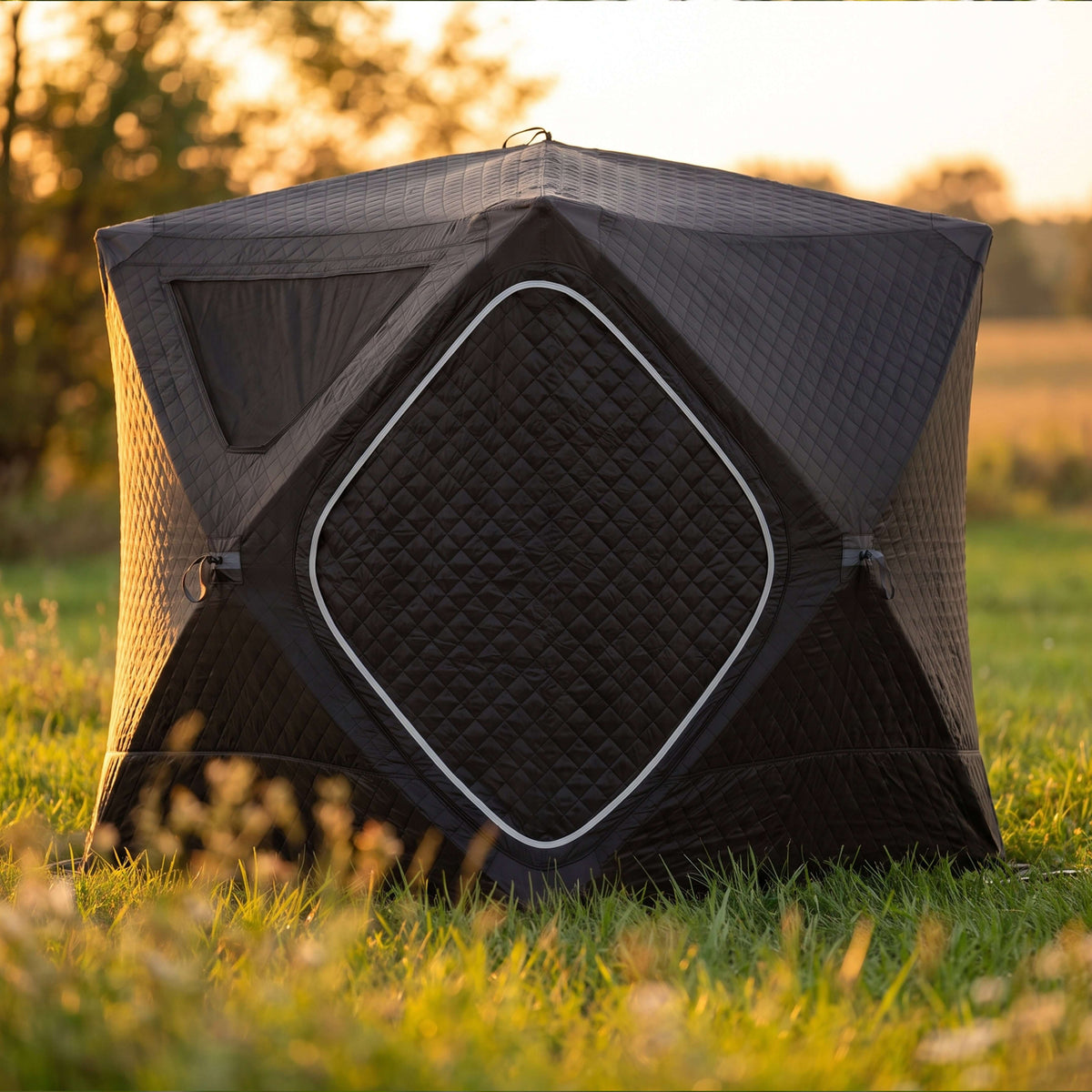 SaunaLife SaunaTrekker Portable Sauna Tent set up in a grassy field during sunset, designed for up to 4 bathers.