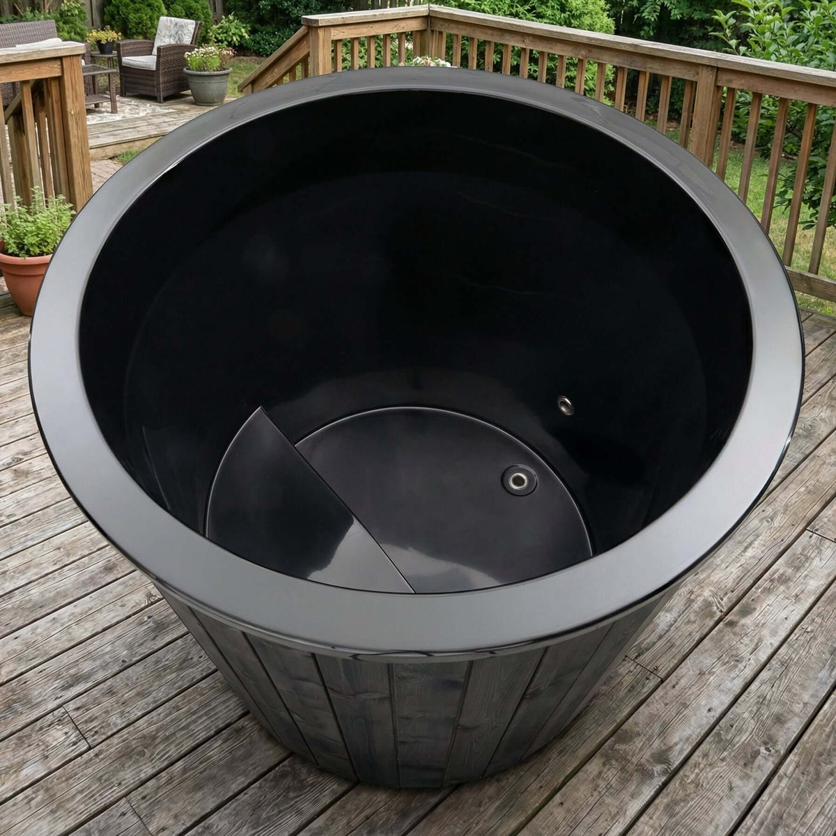 Empty black S1B tub from SaunaLife on a wooden deck with outdoor furniture in the background