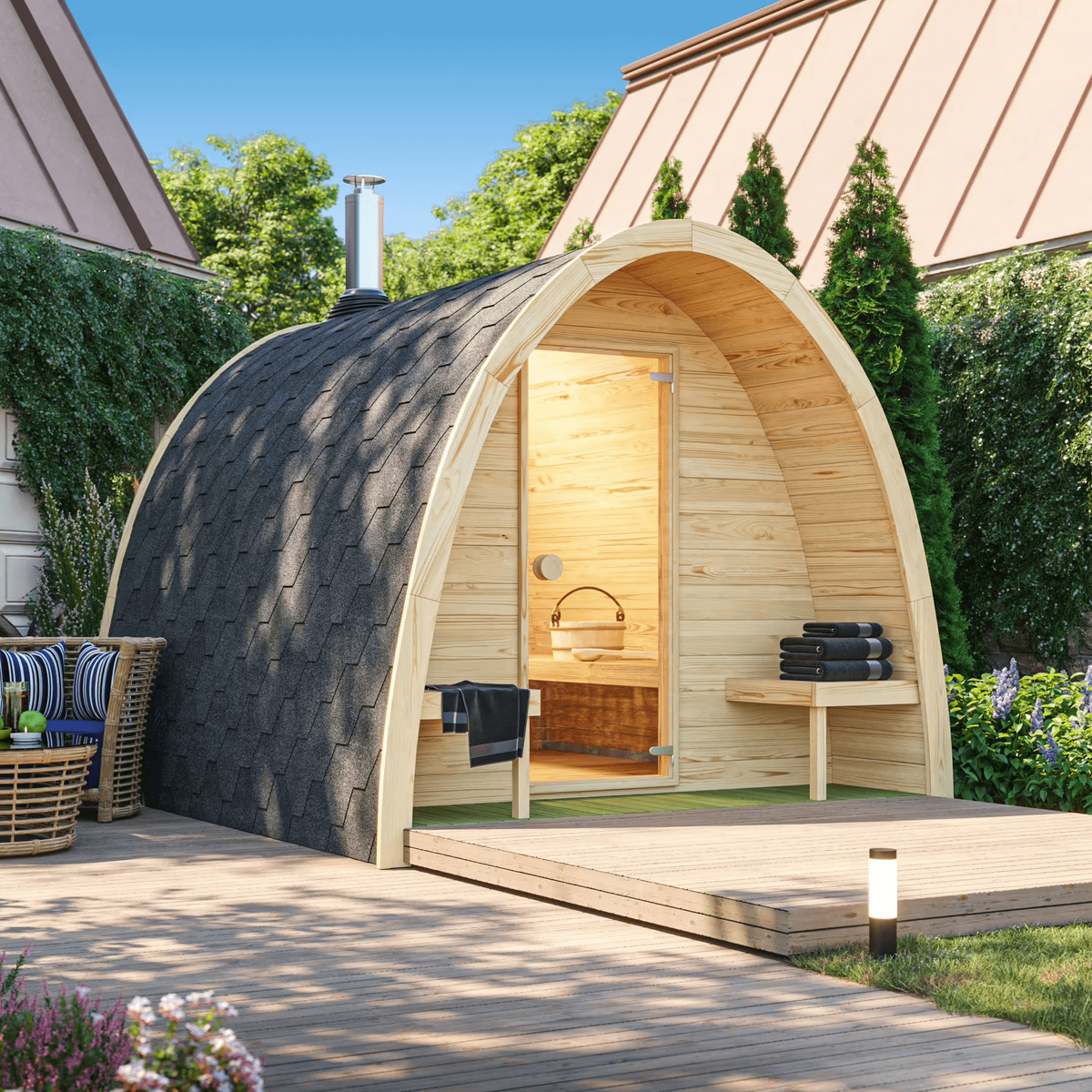 Outdoor Saunalife G3 sauna with a parabolic arched roof, wooden staves and a bronze-tinted glass door, set on a wooden platform with outdoor seating and greenery in the background.