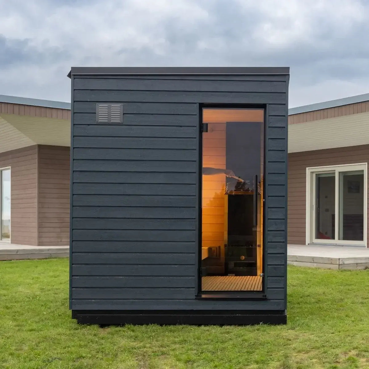 SaunaLife G6 black sauna, facing to the side, with it's glass door, on a grassy area